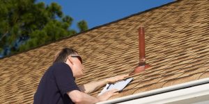 Person with clipboard inspecting the condition of a roof.