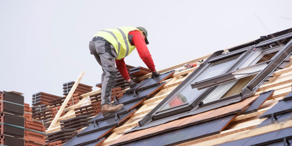 Worker installing a new roof with skylights.