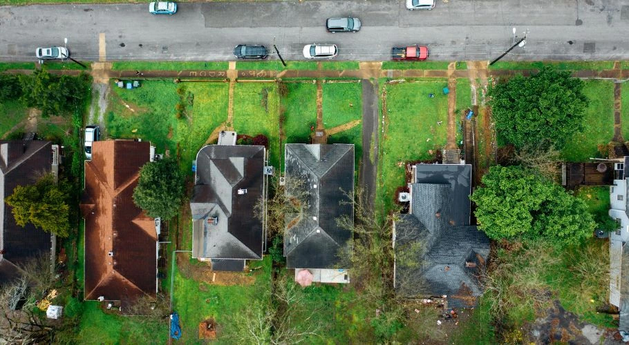 A bird's eye view of houses with dark-colored asphalt shingle roofing.