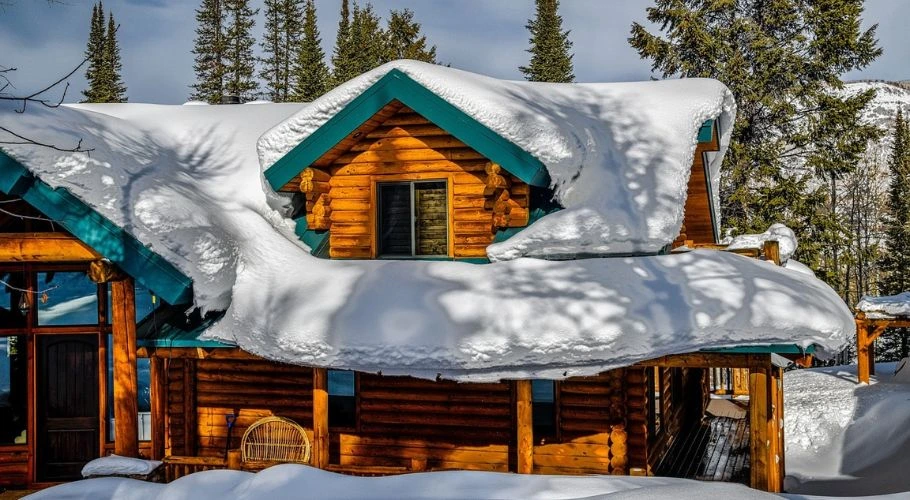 Heavy snow on the roof of a cabin.