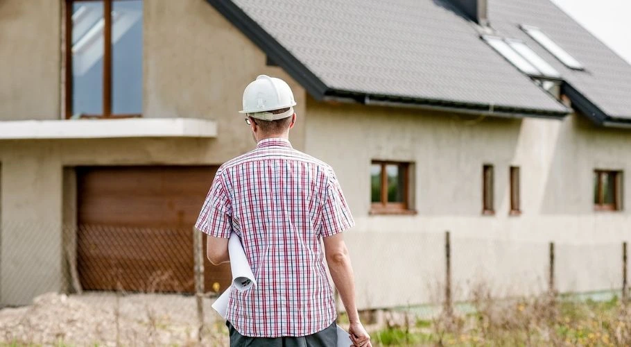 Professional roofer walking toward a house.