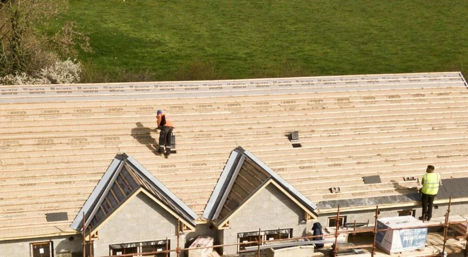 Roofers adding underlayment to a roof.