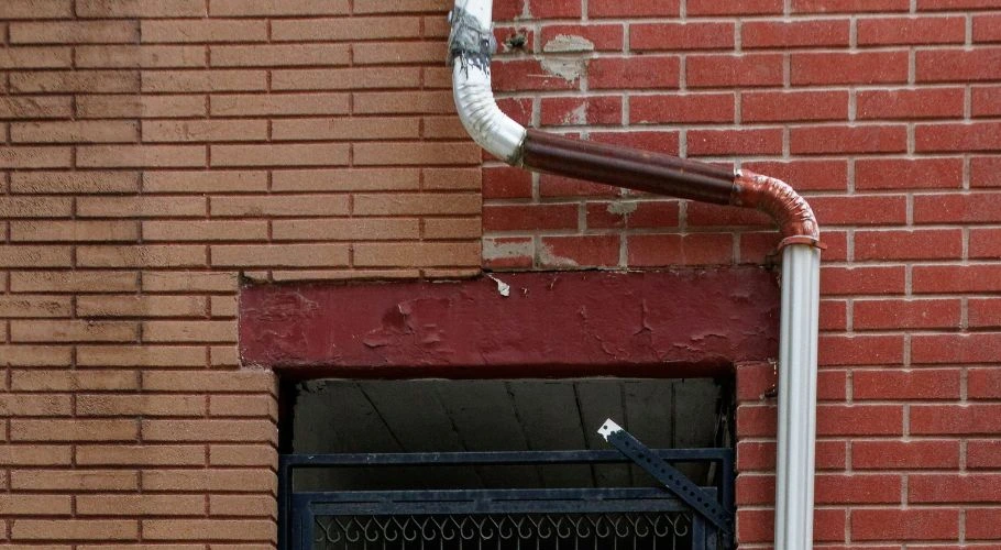 downspout detaching from a brick wall