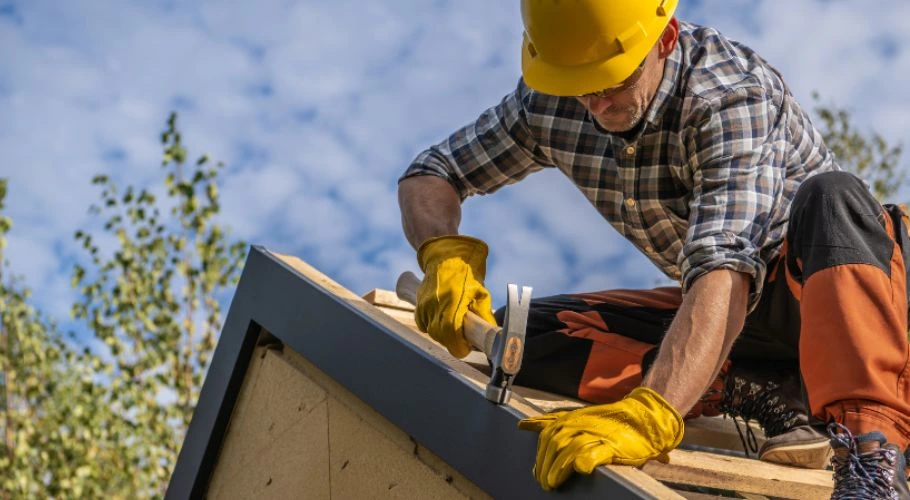 professional roofer nailing down wood after roof inspection